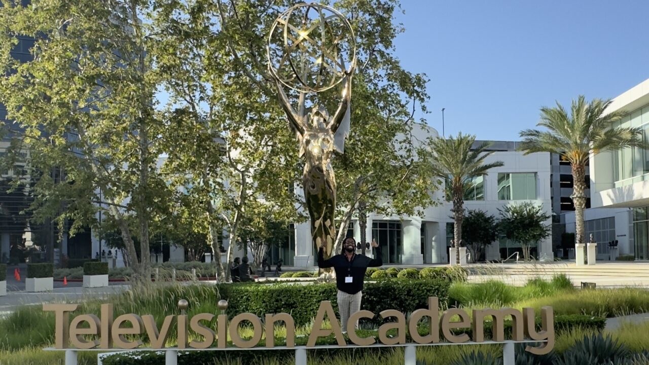 Graduate student Miykael Stith stands in front of an Emmy statue at the Television Academy