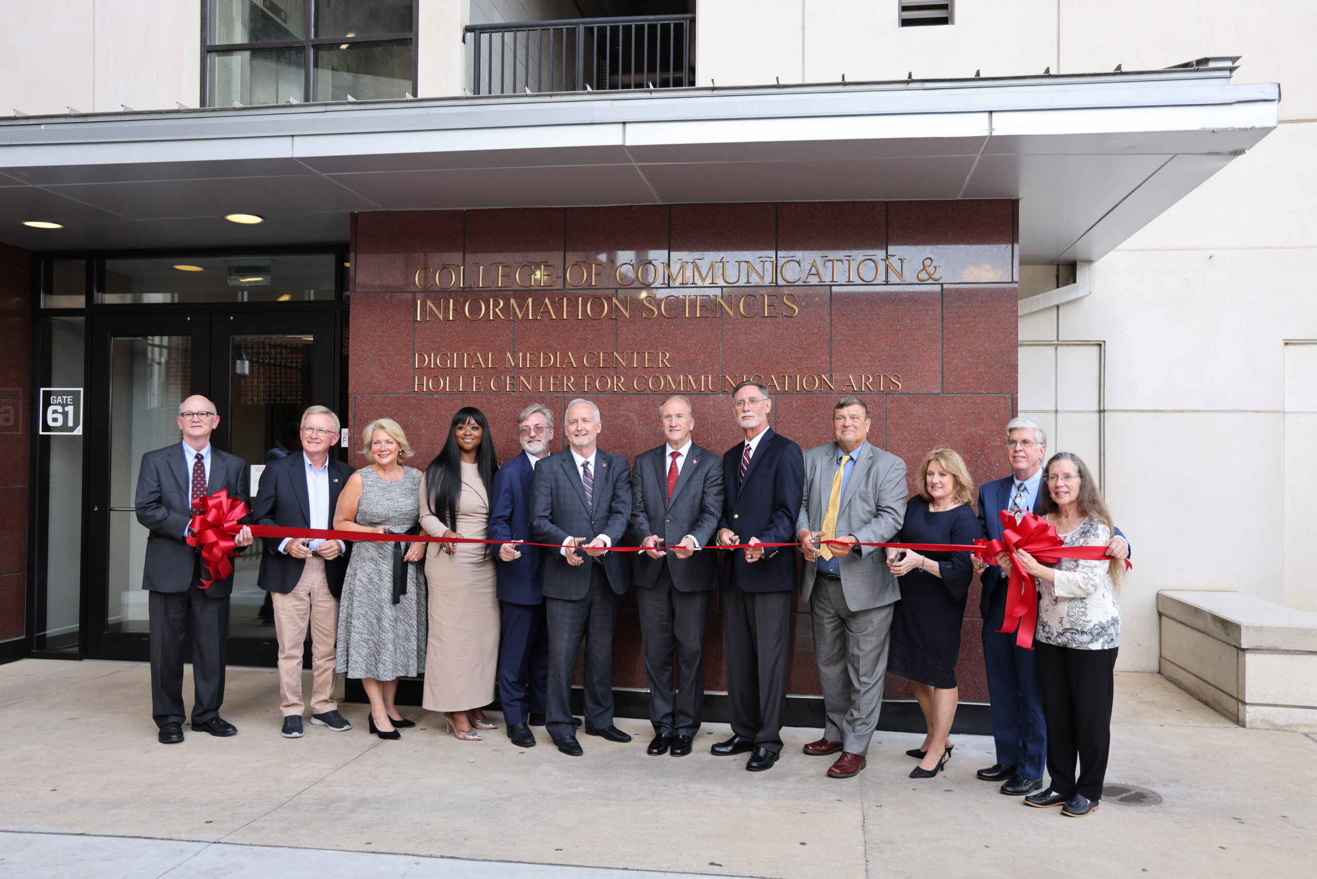 Director Robin Boylorn, Dean Butler and several university leadership cut the red ribbon in front of the Holle Center, marking its opening.