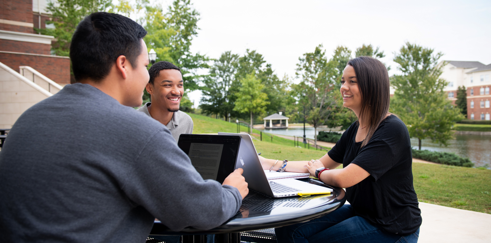 Three students in the LLC sitting at a table outside of John England Hall.