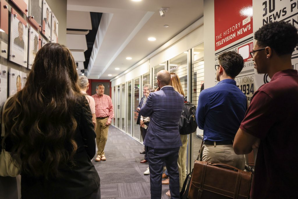 Members of the State Department tour the DMC and standing in a hallway listening to a member of the DMC.