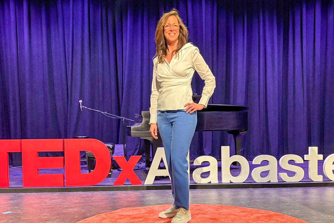 Heather Hayes stands in front of the a sign for TEDx Alabaster.